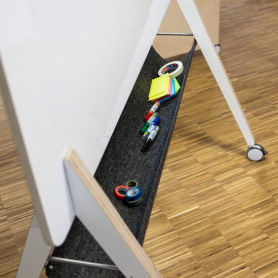eine nahaufnahme eines whiteboards von moveable.space mit dunkelgrauer filzablage und stiften