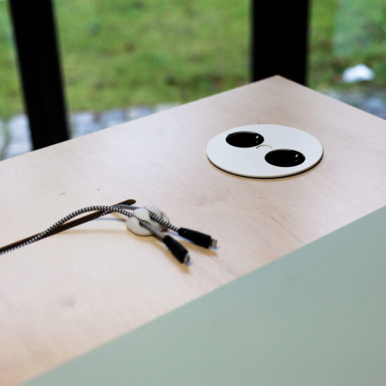 ein detail einer tischplatte von moveable.space mit kabeln und steckdosen