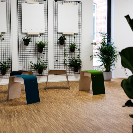 der pop up raum von moveable.space mit drei hockern mit filzbezug in drei verschiedenen farben, an der wand drei metallgitter mit whiteboards und pflanztöpfen