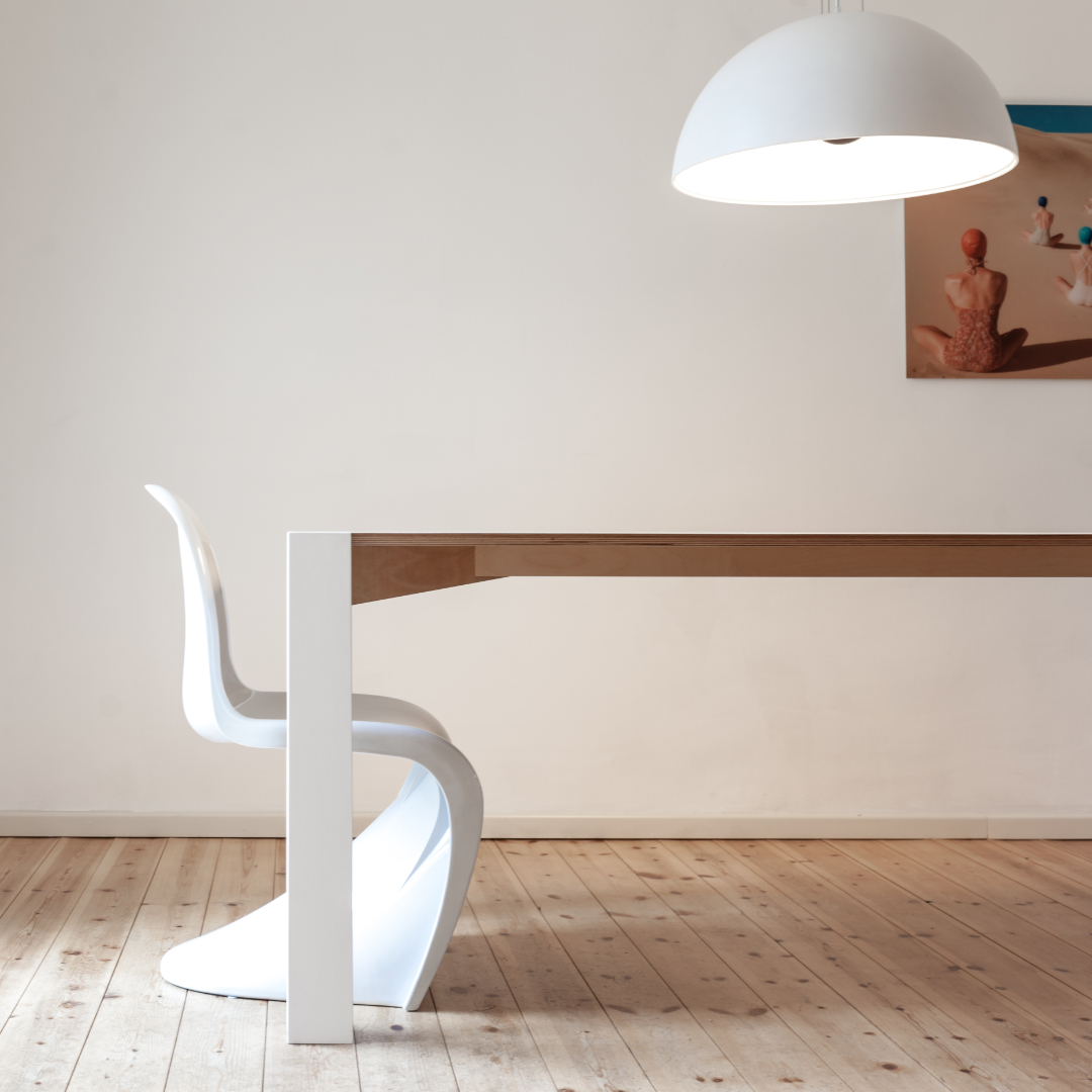 ein esstisch unikat in einem schlichten raum mit holzdielen, und weißem pantonchair