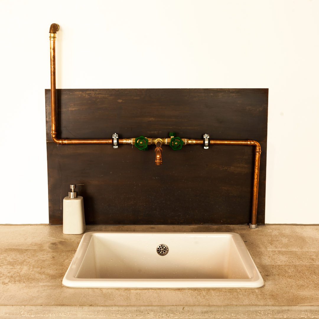 eine küchenwaschbecken sonderanfertigung mit sichtbarer kupferrohrleitung und metallplatte