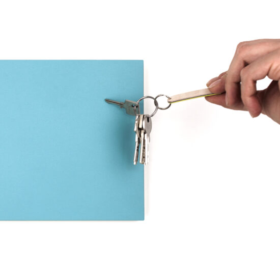 eine hand zieht an einem schlüsselbund, der an einem magnetischen türkisen schlüsselboard hängt