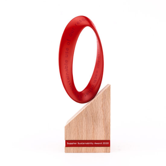 sustainabilty award aus naturholz und rotem element, dass mit schrift versehen ist, unten ein logo cewe